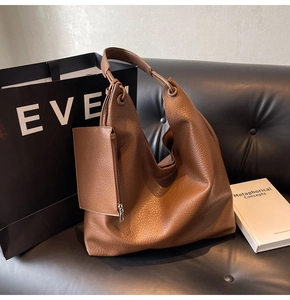 Détail du sac hobo en cuir grainé marron avec mini pochette assortie sur un canapé