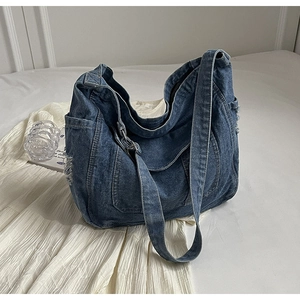 Close-up of deep blue denim tote bag with frayed edges on white textured surface