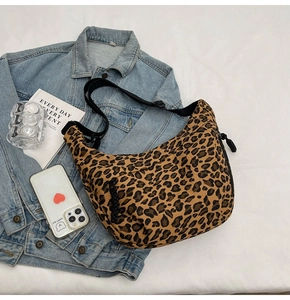 Detail shot of leopard print canvas crescent bag with black strap on casual flat lay