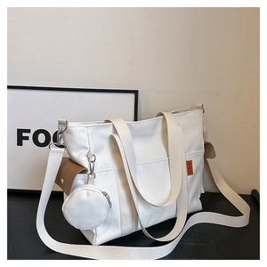 Detail of white canvas tote bag with brown flap pocket and mini round coin purse charm