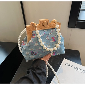 Detail of blue denim seashell bag featuring sequined butterflies and wooden clasp