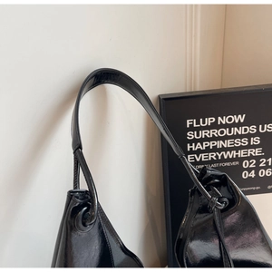 Detail shot of the glossy black faux leather shoulder bag with structured top handle