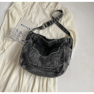 Close-up of washed denim tote with distressed edges and silver metal buckle detailing