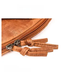 Détail macro de la texture du cuir caramel et des doubles fermetures éclair en métal