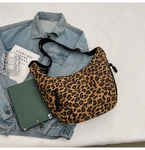 Detailed view of leopard print canvas crescent bag with adjustable black strap and accessories