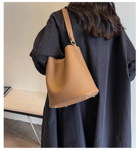 Détail du grand sac seau caramel montrant le cuir grainé et les pieds métalliques