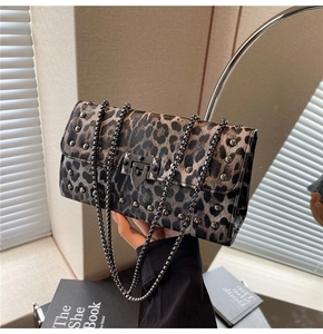 Détail d'un sac à bandoulière léopard avec des rivets en métal et une boucle carrée