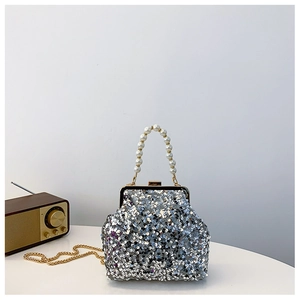 Detail einer silbernen Pailletten-Abendtasche mit weißem Perlengriff und Goldkette