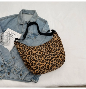 Detail of leopard print canvas hobo bag with adjustable black shoulder strap on denim