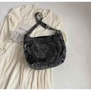 Detail of black washed denim tote bag with side woven ropes and metallic buckle