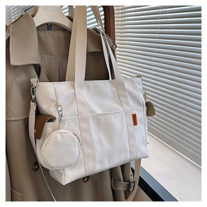 Detail of white canvas tote bag with brown flap pocket and mini round pouch attachment