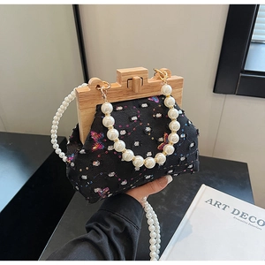 Detail of beaded pearl handle on sequined shell-shaped bag with vintage wooden frame