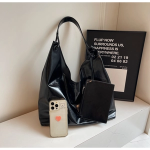 Detail view of high-gloss black leather hobo bag with a matching small zipper pouch
