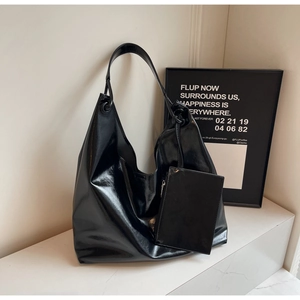 Detail view of glossy black large hobo bag and matching coin purse on white surface