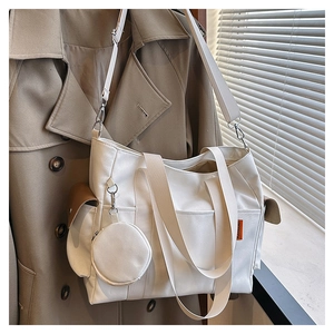 Detail of cream canvas tote bag with mini coin purse charm and adjustable wide shoulder strap