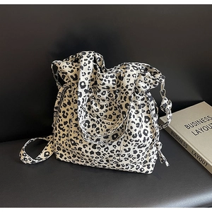 Detail view of black and white leopard print canvas tote bag with drawstring on leather bench