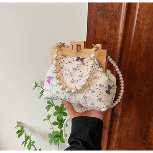 Detail of beaded shell bag featuring sequin butterflies and natural wooden frame