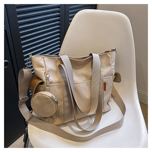 Detail view of beige canvas tote bag with small round coin purse accessory