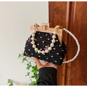Detailed view of vintage black handbag featuring colorful butterfly embroidery and wood frame