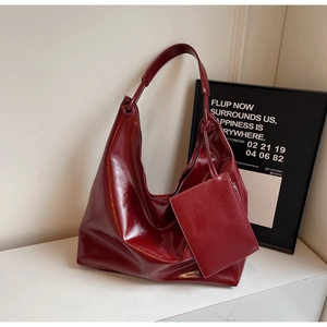 Detail of burgundy glossy patent leather tote bag with matching mini zipper pouch