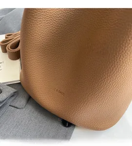Détail du sac seau en cuir marron à texture lychee avec logo et bandoulière souple