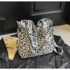 Detail of leopard print canvas tote bag with adjustable straps on leather jacket
