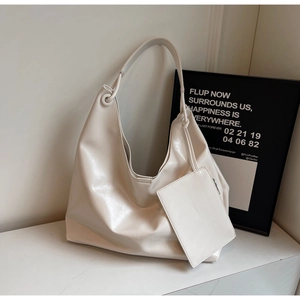 Detail of a beige oversized hobo bag showing wide strap and detachable mini pouch accessory