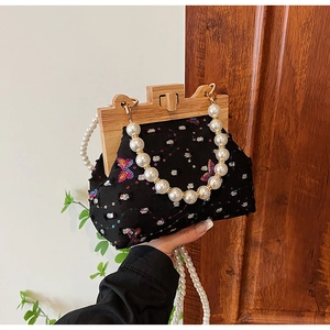 Detail of vintage butterfly embroidery bag with wooden frame and pearl strap