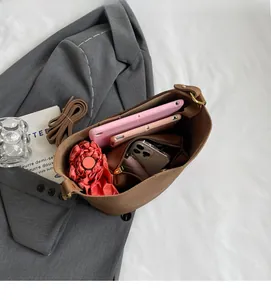 Vue intérieure du sac seau marron montrant sa grande capacité pour parapluie et tablette