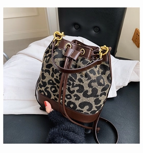 Detail of leopard print canvas bucket bag with brown leather trim and drawstring closure