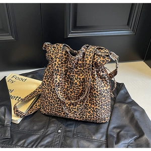 Detail of leopard print canvas tote bag featuring drawstring closure and silver buckle