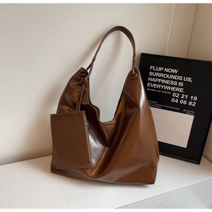 Detail of a large dark brown hobo bag in polished faux leather with a small side pouch