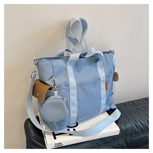Detail of light blue canvas tote bag featuring side pockets and round coin purse accessory