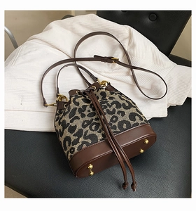 Close-up of leopard print bucket bag with drawstring closure and golden hardware studs