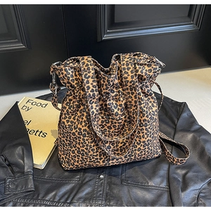 Macro detail of leopard print canvas tote bag featuring silver hardware on leather jacket