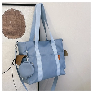 Detailed side view of blue nylon tote bag with leather pocket and small coin purse