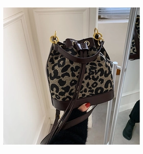 Detail of leopard print canvas bucket bag with brown leather trim and gold rings