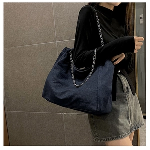 Detail of the chain shoulder strap on a large capacity navy denim tote bag for women