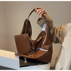 Detail view of glossy brown hobo tote set with matching pouch on minimalist background