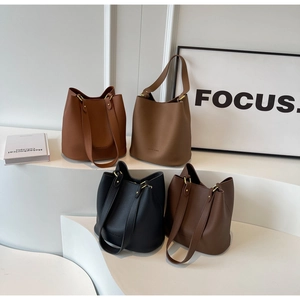 Quatre couleurs de sacs seau en cuir grainé présentés sur des marches blanches modernes