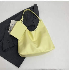 Vue à plat d'un sac cabas en cuir jaune pâle avec pochette assortie sur blazer gris
