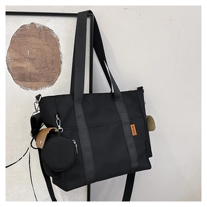 Detail of black canvas tote with orange label, khaki side pocket and mini coin purse