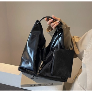 Close-up of black glossy patent leather hobo bag with a matching small zipper pouch