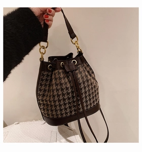 Detail of retro houndstooth bucket bag with brown leather trim and drawstring closure