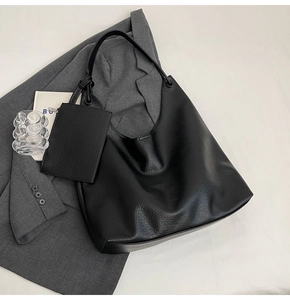 Détail d'un grand sac hobo noir avec texture litchi et une petite pochette assortie