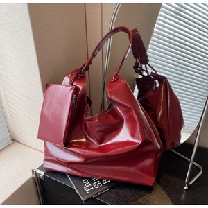 Detailed close-up of glossy burgundy faux leather hobo bag with matching mini coin purse