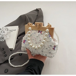 Detail of beaded pearl handle on white shell bag with sequined butterfly embroidery