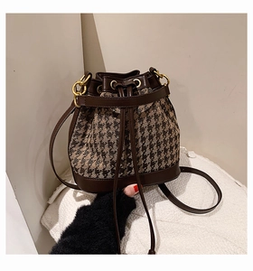 Detail of drawstring bucket bag with houndstooth pattern and brown leather finish
