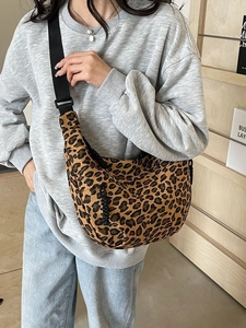 Leopard print canvas crossbody dumpling bag with adjustable strap worn by model