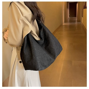 Detail of large denim tote bag showing its texture and drape on a model's shoulder